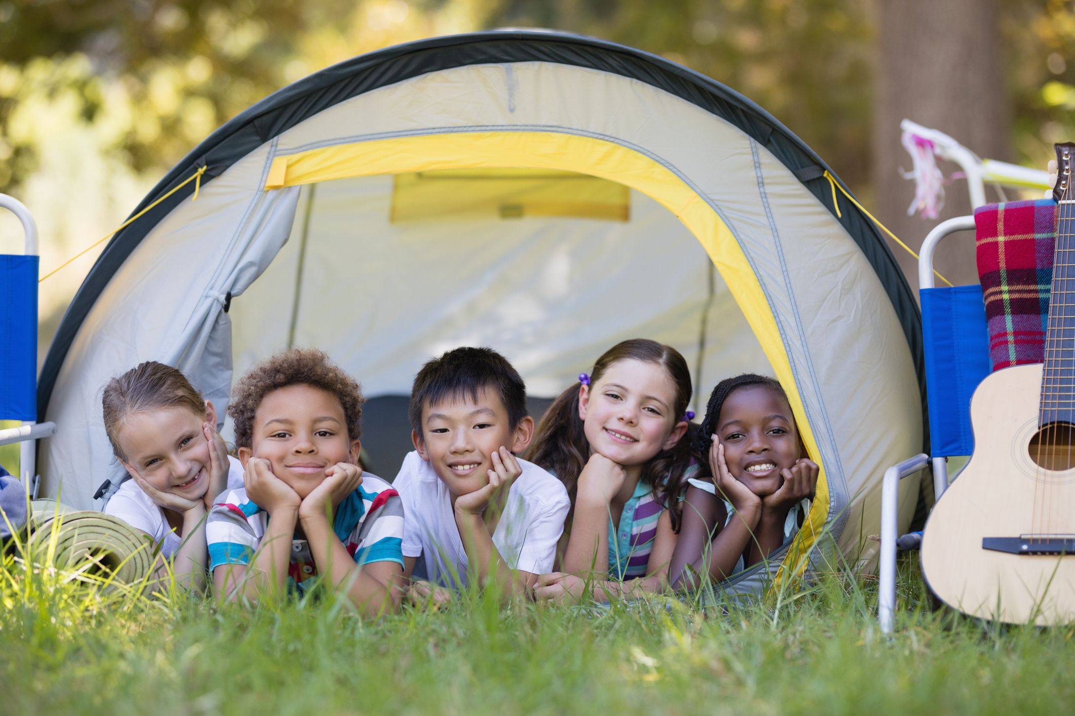 Portrait of smiling friends resting in tent at campsite